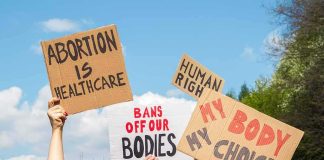 Protesters hold cardboard signs at a rally outdoors
