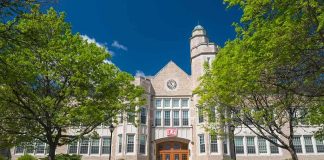 Historic academic building with clock tower framed by green trees