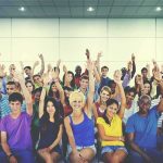 Group of people raising hands in an indoor audience
