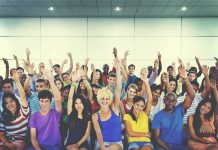 Group of people raising hands in an indoor audience
