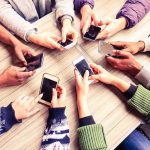 Soros Empire Isn’t Dead—It’s Shedding Skin Hands around a table holding smartphones