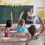Students raise hands in classroom during lesson