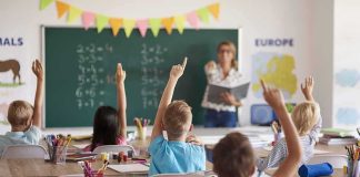Students raise hands in classroom during lesson