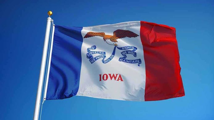 shutterstock_549472498 Iowa state flag waving on a flagpole against a clear blue sky