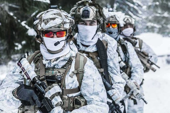Soldiers in white winter camouflage gear standing in a snowy forest