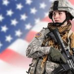 AI Veterans Scam Explodes on TikTok Soldier in camouflage holding a rifle against a blurred American flag