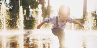 child splashing in a sunlit fountain