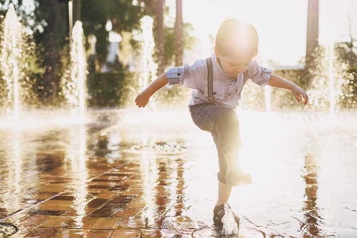 child splashing in a sunlit fountain