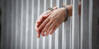 Couple Convicted in $13M Aid RIPOFF handcuffed hands resting through prison bars