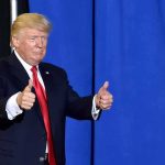 Trump’s Blunt Take on Being SUED Donald Trump giving two thumbs up in front of a blue curtain