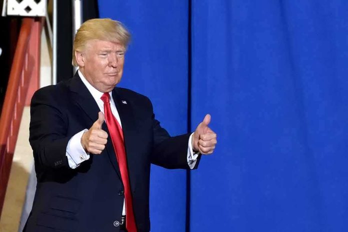 shutterstock_1087344797-1 Donald Trump giving two thumbs up in front of a blue curtain