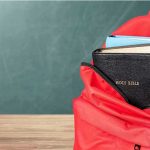 Red backpack with books on a classroom desk
