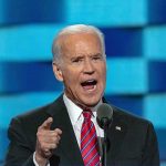 Joe Biden speaking at a podium with a microphone, gesturing with his finger