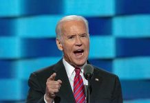 Joe Biden speaking at a podium with a microphone, gesturing with his finger