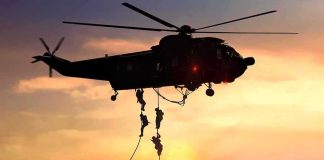 military helicopter with soldiers fast-roping at sunset