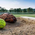 Parents BRAWL at 12-Year-Old Girls’ Softball Game Softball and glove near a base on a dirt field
