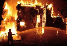 A firefighter battling a large house fire at night