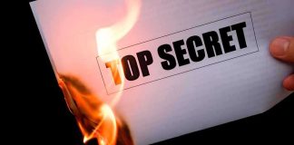 A hand holding a lighter igniting a paper labeled TOP SECRET as it catches fire