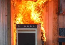 Kitchen stove engulfed in flames against a wall