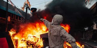 40,000 Rioters Hit Paris Streets Hooded person throws object near street fire