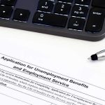 Unemployment benefits application form with keyboard and pen
