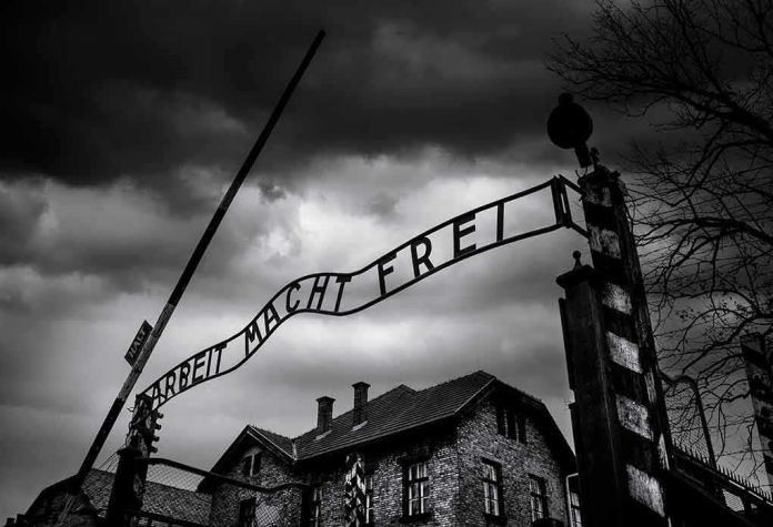 Entrance gate with wrought-iron sign at a historic brick complex under stormy skies