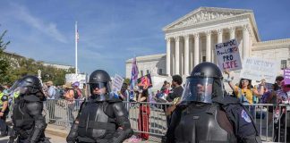 Riot police stand in front of a courthouse during a protest
