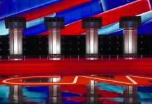 Debate stage with four empty podiums and bright red and blue backdrop