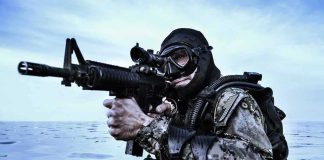 Combat diver aiming rifle in open water