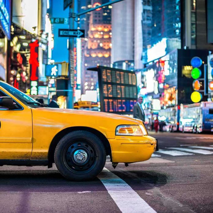 Yellow taxi at a city crosswalk at night