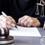Man Awarded $67,500 Over His Ex’s ABORTION Judge writing at desk with gavel and Lady Justice statue