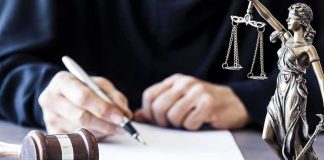 Man Awarded $67,500 Over His Ex’s ABORTION Judge writing at desk with gavel and Lady Justice statue