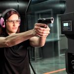 Female Gun Ownership SURGES Across America Woman aiming a handgun at an indoor shooting range