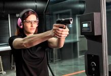 Woman aiming a handgun at an indoor shooting range