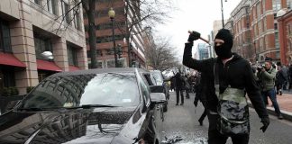 Rioters DESTROY 143-Year-Old Town Hall Masked protester raises tool to strike black car on city street